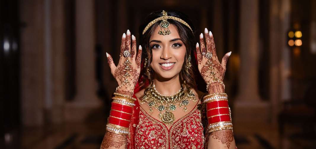 Smiling bride displaying her raised henna-covered hands