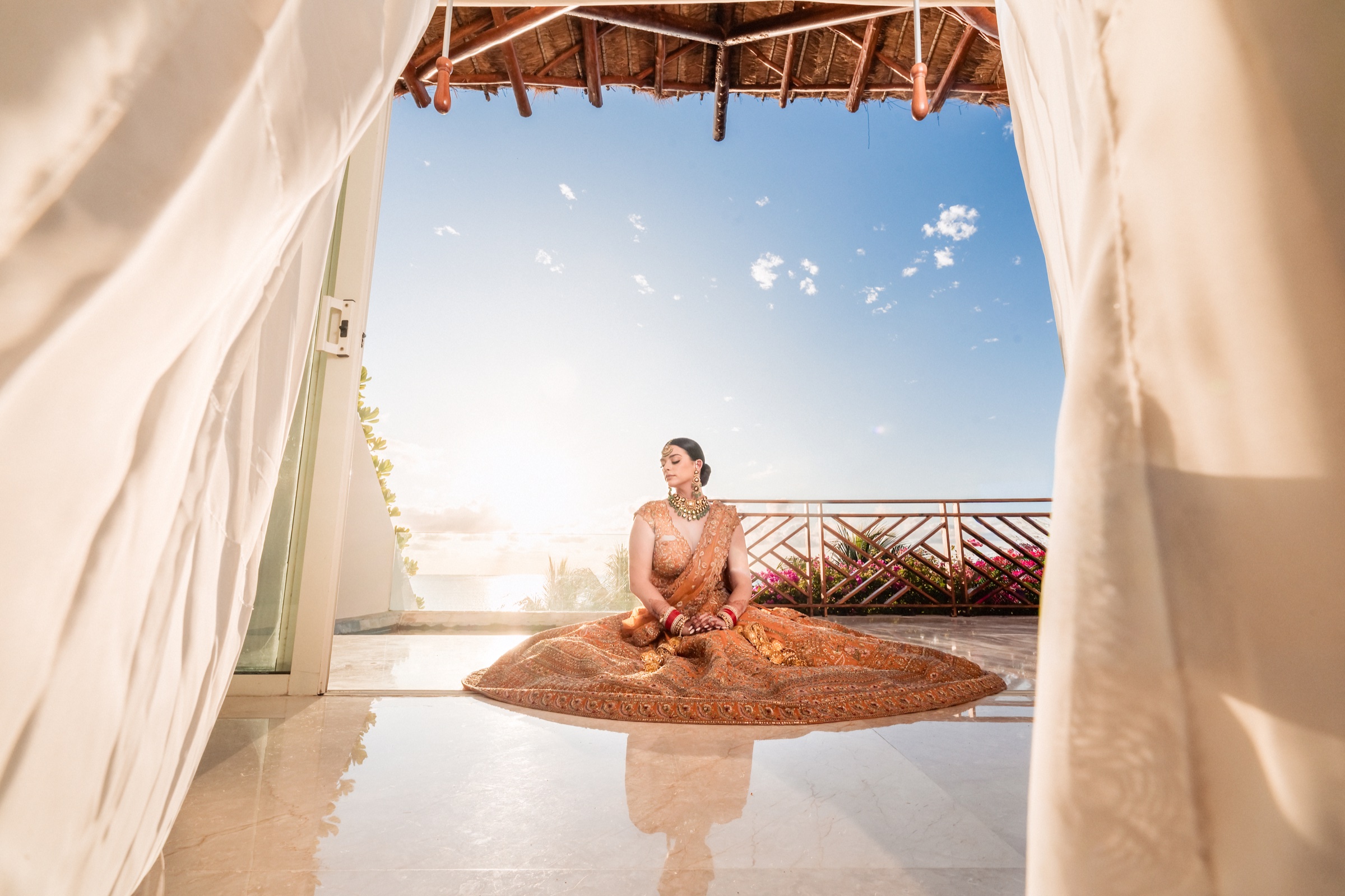 Lauren in her spread-out bridal gown, framed by curtains overlooking the ocean