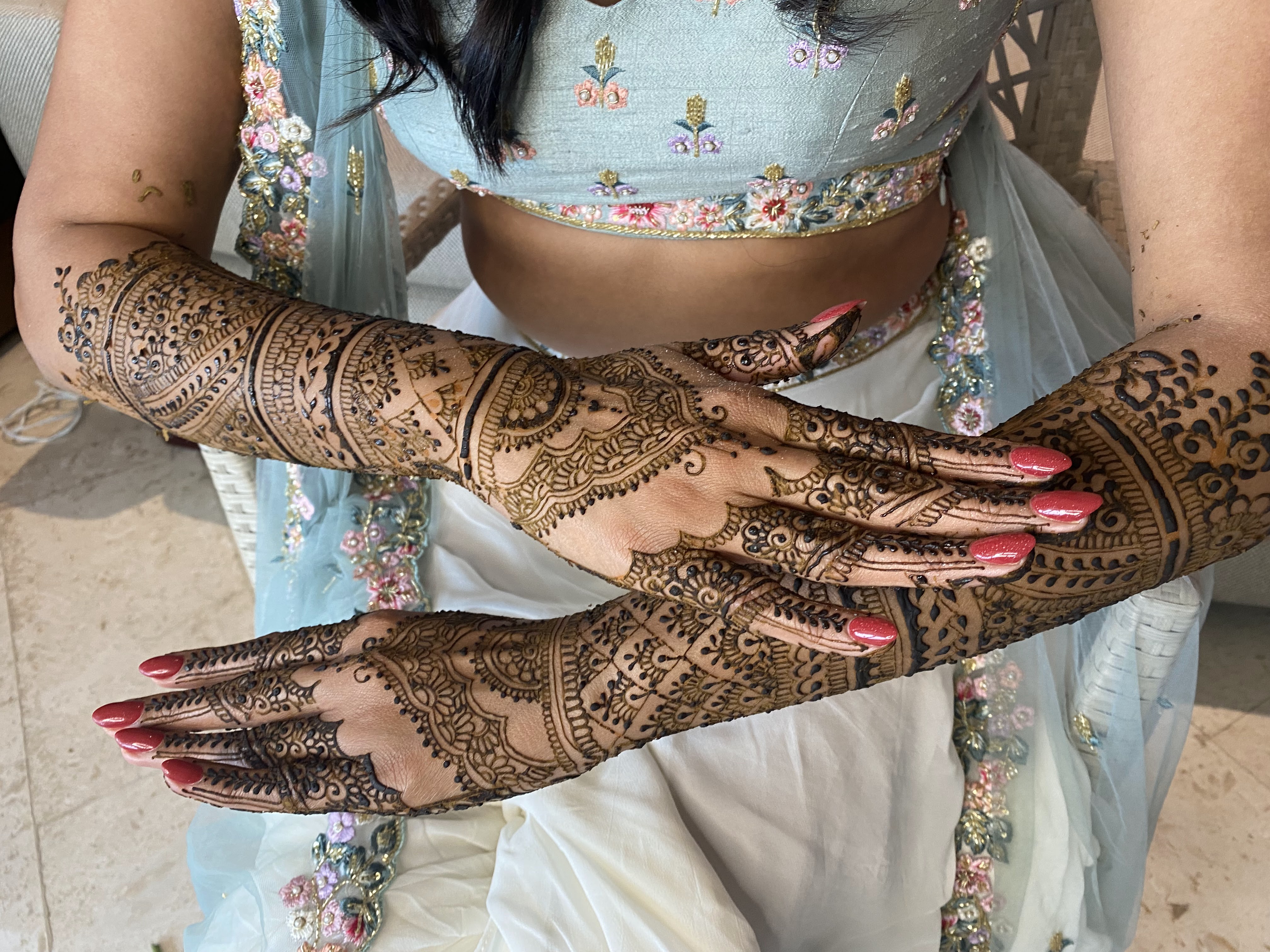 Patrones de henna nupcial detallados en ambas manos y antebrazos