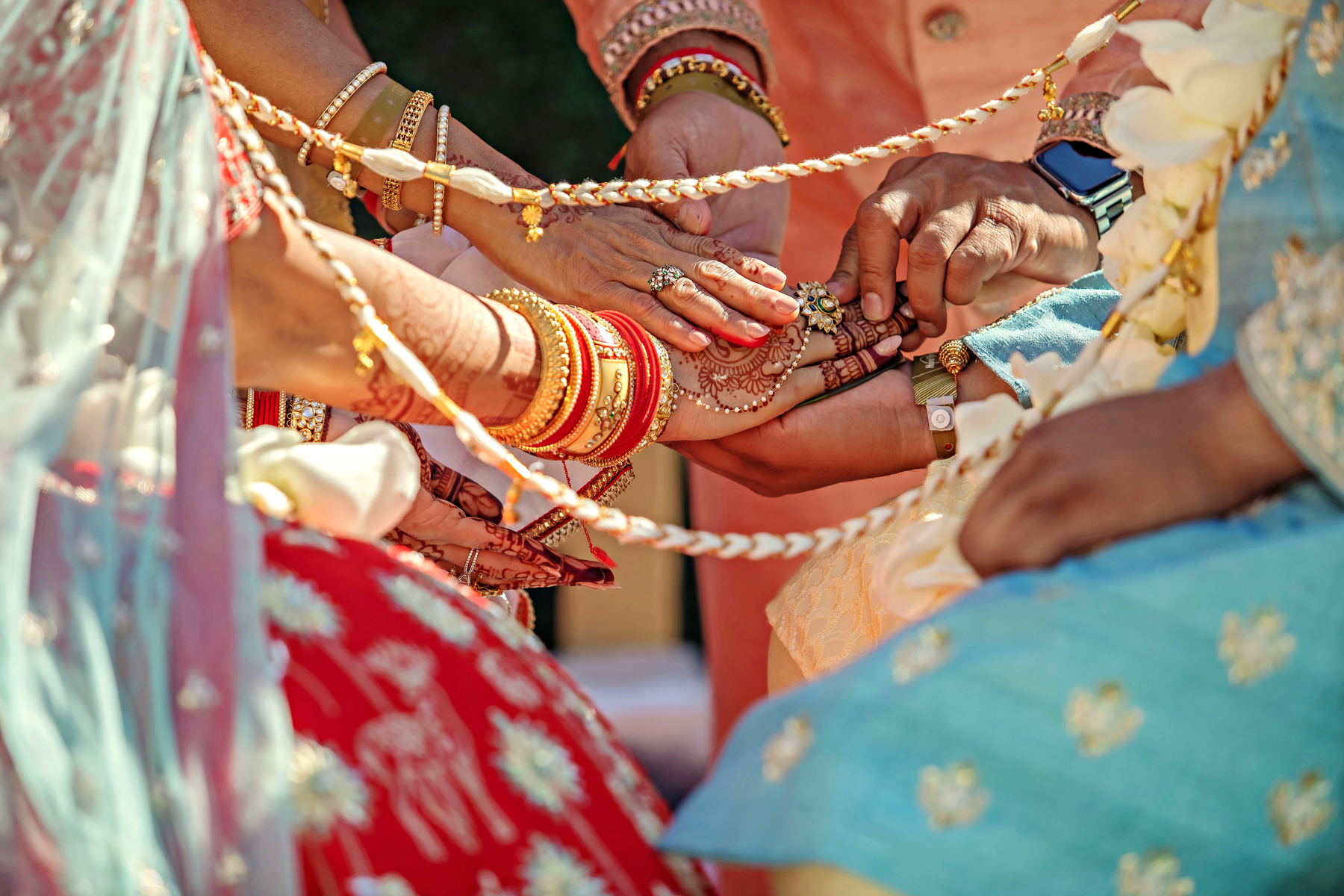Manos de novia con henna, brazaletes rojos y dorados, anillos y joyería de ceremonia